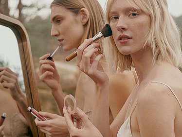 DOUGLAS Customers using makeup products in a lush wild landscape