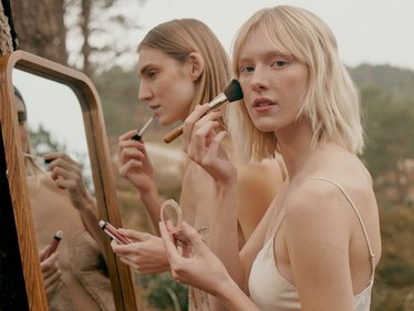 DOUGLAS Kundinnen verwenden Make-up vor einer grünen weitläufigen Landschaft
