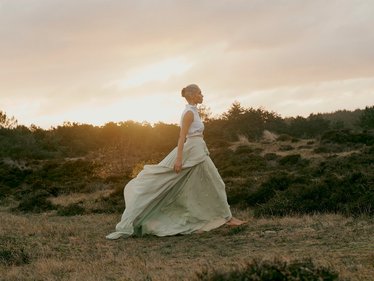 Eine Frau läuft bei Sonnenaufgang über eine Wiese