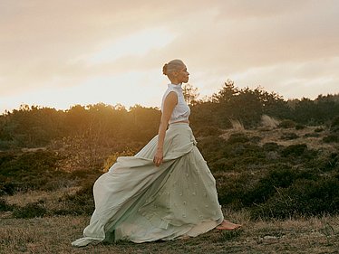 Woman walking across a meadow at sunrise