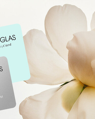 DOUGLAS Beauty Cards vor einem weißen Hintergrund mit einer Blume